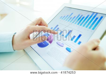 Picture or Photo of Close-up image of an office worker using a touchpad to analyze statistical data