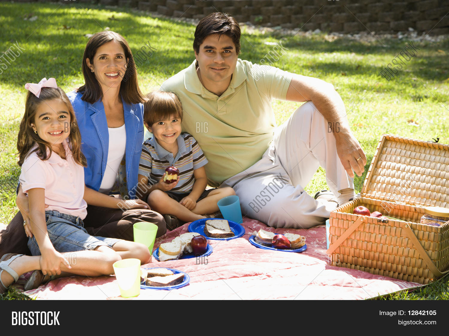 Hispanic family picnicing in the park and smiling at viewer. Stock