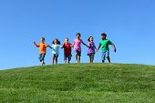 stock photo of group  - Kids running on grass hill with blue sky - JPG 