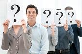 pic of leadership  - Happy smiling business man standing out of the crowd with other people hiding their face behind a question mark sign - JPG 