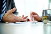 foto of meeting  - Image of male hand pointing at business document during discussion at meeting - JPG 