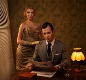 image of newspaper  - Man in suit reading newspaper with woman behind him - JPG 