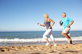 image of health  - Senior Couple In Fitness Clothing Running Along Beach - JPG 