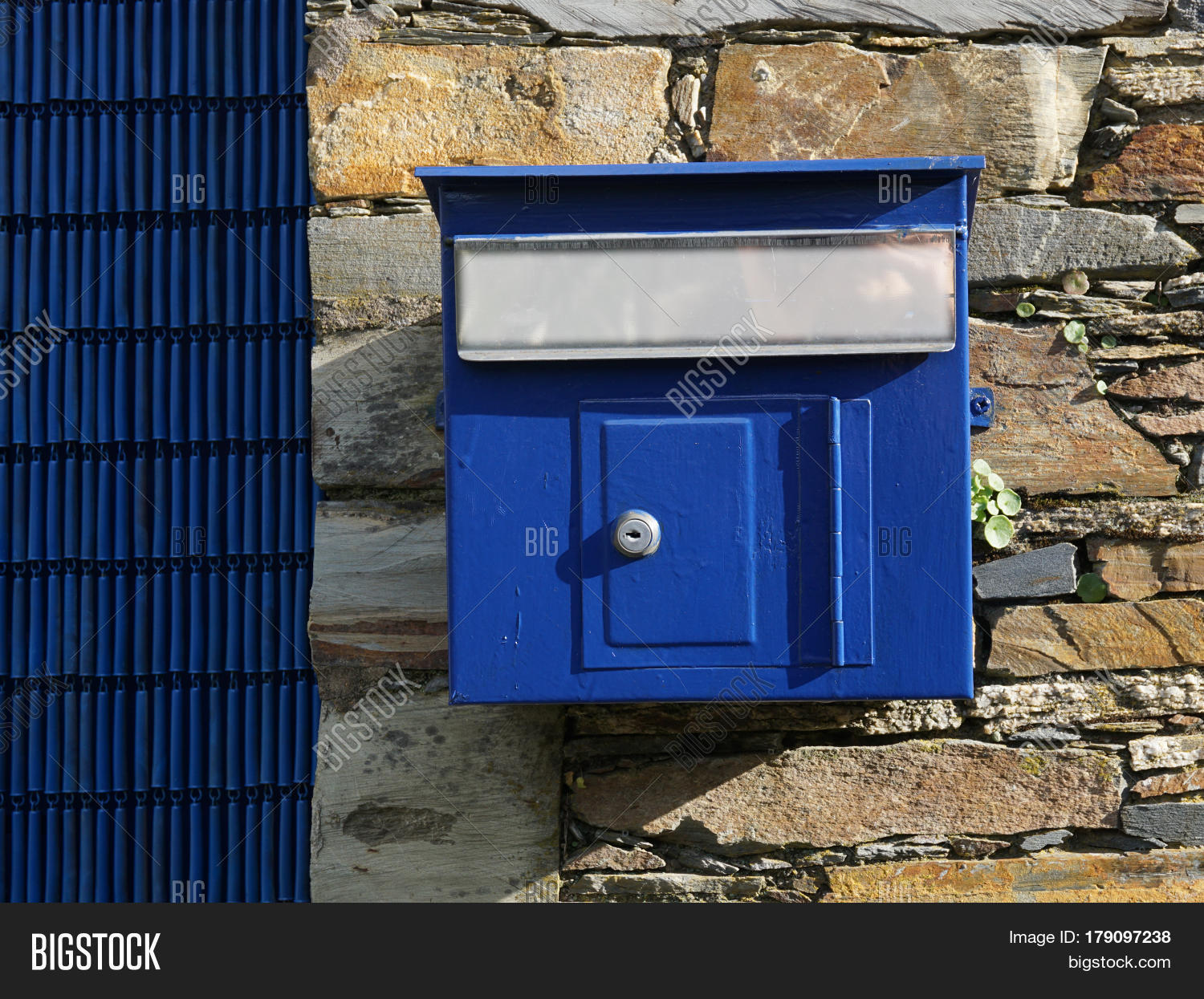 Old blue mailbox hanging on the stone fence. Stock Photo & Stock Images