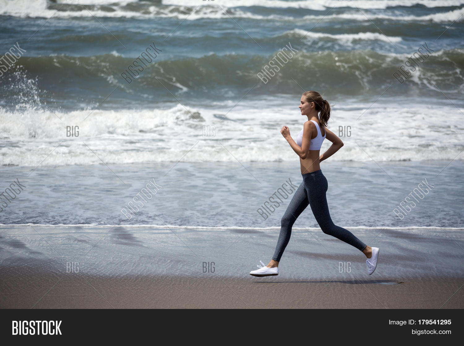Young sporty woman running on the beach. Stock Photo & Stock Images