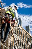 stock photo of construction worker  - A construction worker on a high wall against a cloudy sky - JPG 