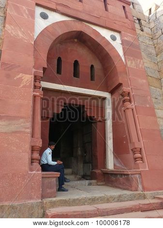 DELHI INDIA - NOVEMBER 4: Unidentified man sits at Mausoleum at Tughlaqabad Fort on November 4 2014 in Delhi India. Tughlaqabad Fort was built by Ghiyas-ud-din Tughlaq founder of Tughlaq dynasty