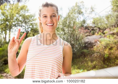 Portrait of pretty blonde showing peace sign and taking selfies in the nature