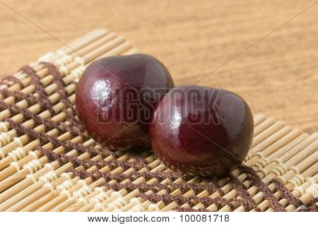 Two Red Plums On A Wooden Plate