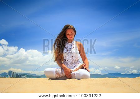 Girl In Lace In Yoga Asana Lotus On Beach Against Blue Sky