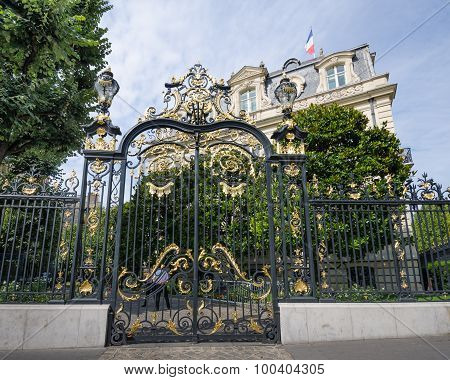 The sun glistens on the gold of an ornate gate in Paris
