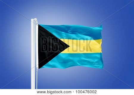 Flag of Bahamas flying against a blue sky.