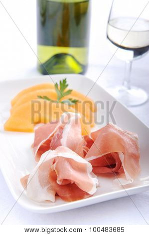 Parma ham served with rockmelon, a common Italian antipasto with a glass of wine 