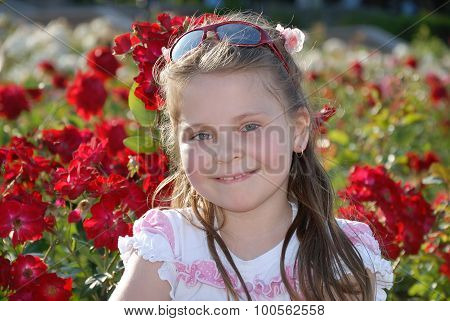 Portrait of the little smiling girl against red roses
