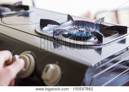 Hand Switching A Knop On A Stove, Close Up