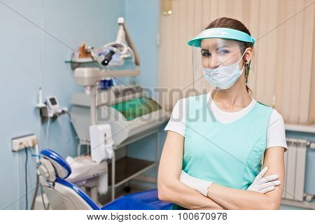 Girl Dentist In Protective Workwear With Protection Face Shield, Mask And Gloves In Her Office