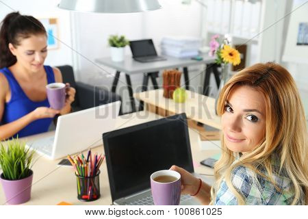 Two Female Designers In Office Drinking Morning Tea