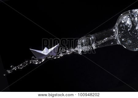 Paper Boat Rides On A Water Splash Out Of A Bottle Against Black Background