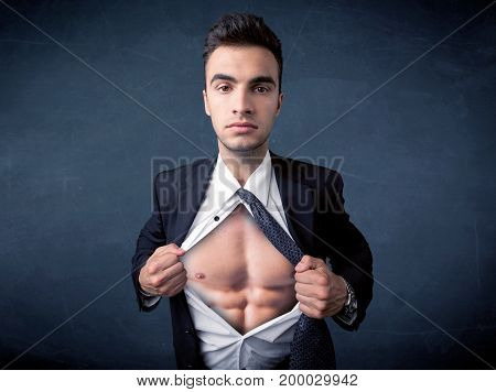 Businessman tearing off his shirt and showing mucular body concept on background