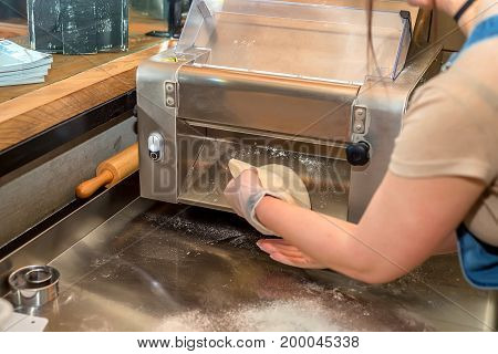 Person working on dough sheeting roller close up