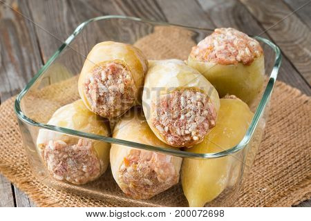 Frozen stuffed pepper in a container on a wooden background