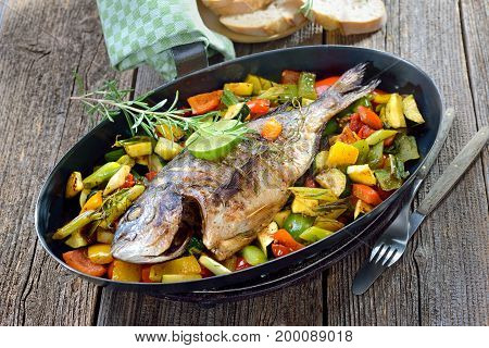 Oven fresh gilthead baked with rosemary on mixed summer vegetables, served with Italian ciabatta bread