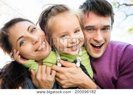 Low angle view portrait of happy smiling family in autumn. Focus on woman