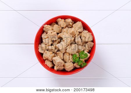 bowl of soy meat cubes on white wooden background