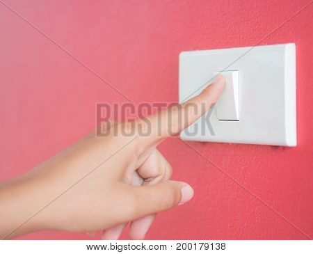Soft focus woman hand turn on the light with red blackground.