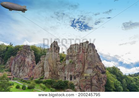 Airship zeppelin flying over the Externsteine taking photo taken in front of dramatic sky. Markant sandstone rock formation in the Teutoburg Forest Germany North Rhine Westphalia.