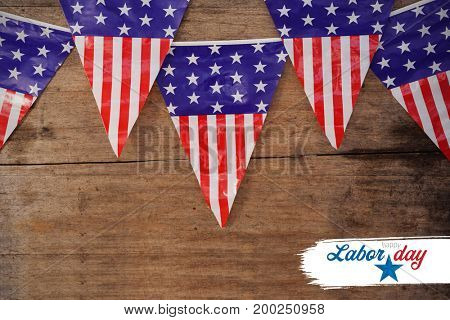 Digital composite image of happy labor day text with star shape against american flag buntings on table