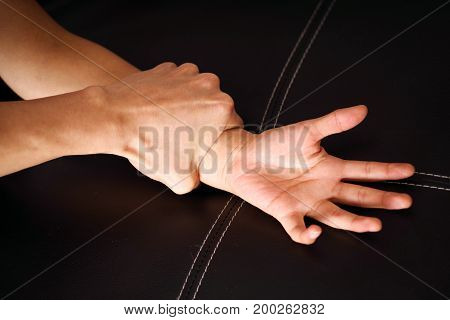 Close up man's hand holding a woman wrist over a black coach for rape and sexual abuse concept.