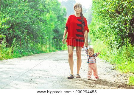 The child learns to walk in the park barefoot on the grass