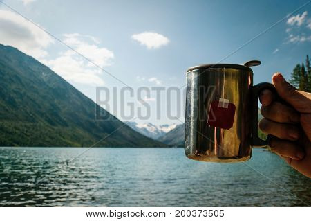 Closeup Photo Of Thermos Mug With Tea In Traveler's Hand