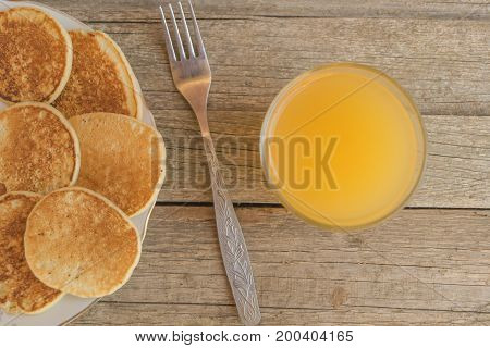 Breakfast with pancakes and orange juice with metal fork on a wooden table
