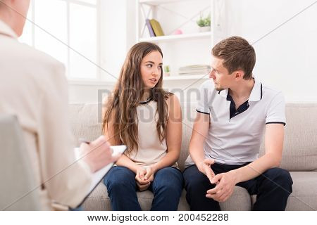 Young couple arguing on couch during therapy session. Relationship problems, family issues concept