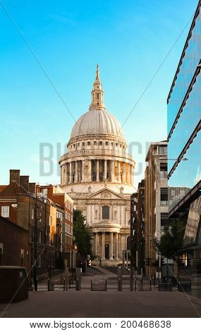St Paul's cathedral seen from a narrow alley enclosed by glass and brick buildings in the morning dawn.London, United Kingdom.
