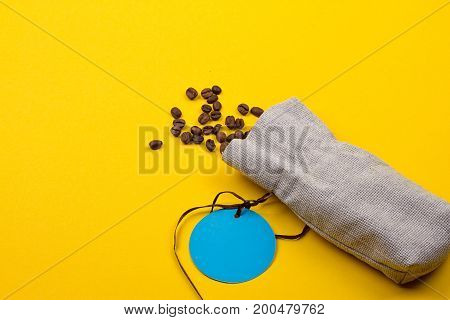 Burlap sack full of coffee beans on yellow background