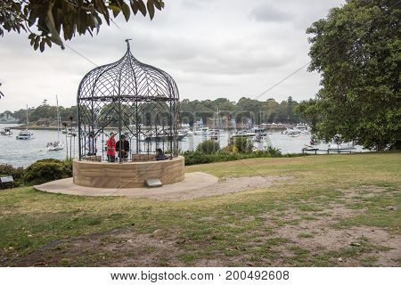 SYDNEY,NSW,AUSTRALIA-NOVEMBER 19,2016: Tourists by metal gazebo at the Royal Botanic Gardens overlooking nautical vessels at Farm Cove for The Plot 2016 concert in Sydney, Australia