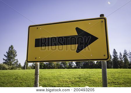 A yellow sign pointing right to direct traffic