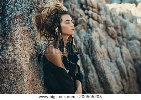 fashion model portrait outdoors. boho style young woman with headdress made of feathers