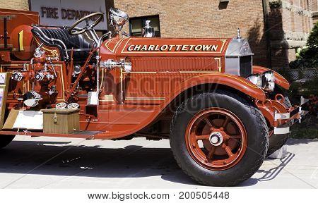 Charlottetown, Prince Edward Island - August 21, 2011 - Wide close up view from the side of the front section of an antique 1929 Fire Truck on display in front of a Firehouse in Charlottetown, Prince Edward Island on a bright sunny day in August.