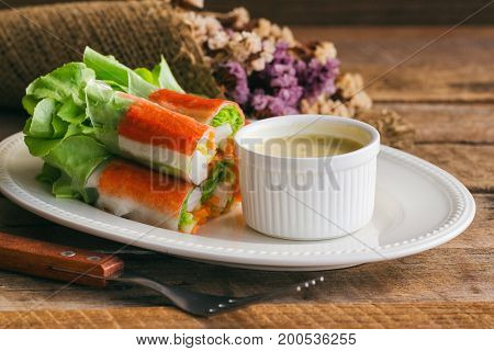 Fresh spring rolls with fresh vegetable and crab stick served with spicy salad cream dipping sauce. Rolls salad or fresh spring roll on white plate healthy delicious food for appetizer or meal. Fresh spring rolls with fusion food style.