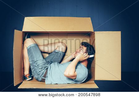 Introvert concept. The man sitting inside the box with headphones