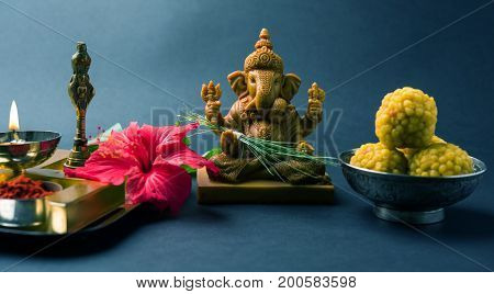 Happy Ganesh Chaturthi Greeting Card showing photograph of lord ganesha idol, pooja or puja thali, bundi laddu/modak, durva and hibiscus or jasvand flower
