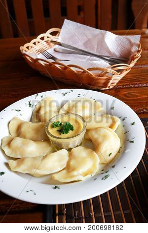 Ukrainian and Russian dish vareniki with mashed potatoes and sour cream and mushroom sauce on white plate. Close up