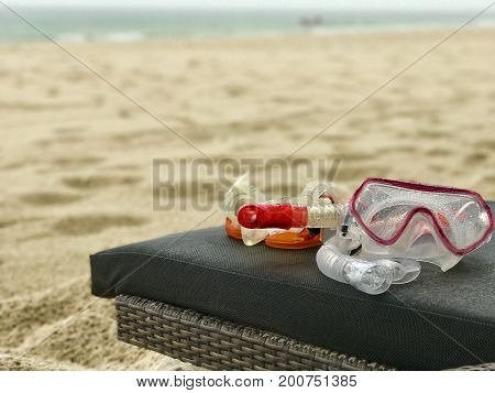 Snorkel and diving mask snorkeling equipment on a deckchair on a white sand beach and sea view