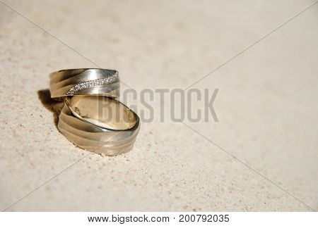 Wedding rings on sand in the sun