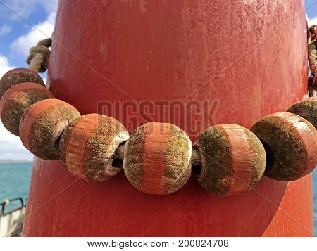 Single row of Parral Beads hanging around a mast with sea and sky in the background. Parral Beads are used to help the sail go up and down the mast. Space for text.