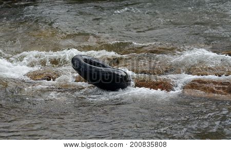 Empty black inner tube descending white water rapids without rider at Clear Creek White Water Park in Golden Colorado